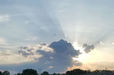 Low angle view of sunlight streaming through clouds