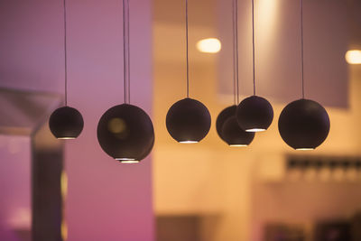 Low angle view of illuminated pendant lights hanging from ceiling