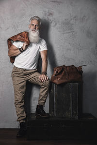 Portrait of young man sitting on chair against wall