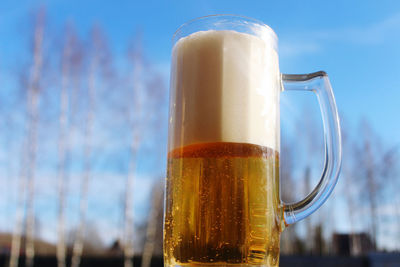 Close-up of beer glass bottle against sky
