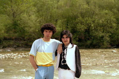 Portrait of friends standing on landscape against trees