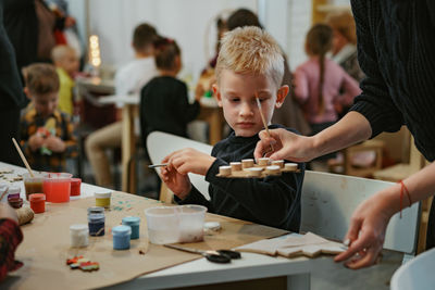 Midsection of teacher assisting student in classroom