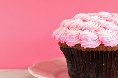 Close-up of cupcake in plate on table against pink wall