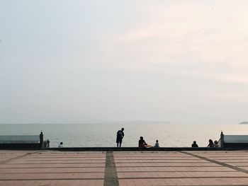 People on beach against sky during sunset