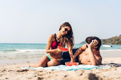 Couple enjoying watermelons at beach