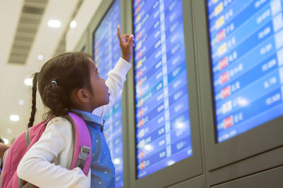 Girl reading arrival departure board at airport