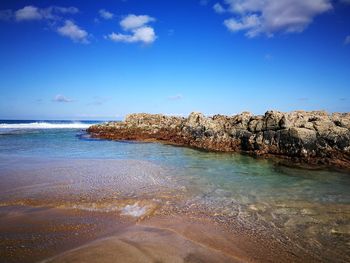 Scenic view of beach against blue sky