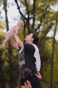 Mother carrying son with girl by trees