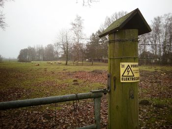 Information sign on field against sky