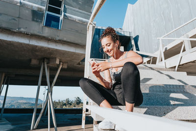 Smiling athlete using smart phone on steps