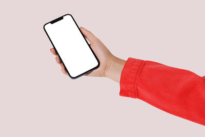 Cropped hand of woman using mobile phone against white background