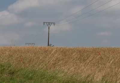 Electricity pylon on field against sky