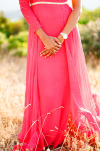 Midsection of woman holding red while standing on field