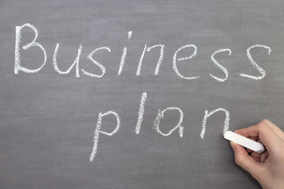 Cropped hand of woman writing business plan on blackboard