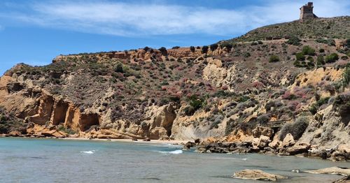 Rock formations by sea against sky