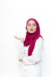 Portrait of young woman standing against white background