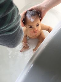 Cropped image of father bathing baby boy in bathtub