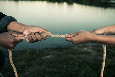 Cropped hands of people holding rope