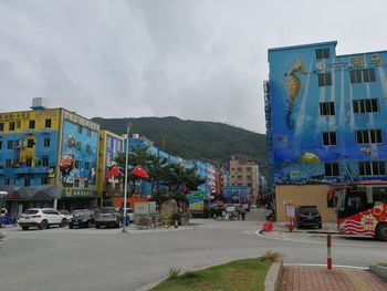 Road by buildings against sky in city