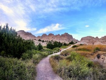Trail leading towards mountains against sky in the badlands