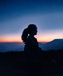 Silhouette woman standing on mountain against sky during sunset