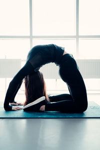 Full length of woman lying down on floor against window