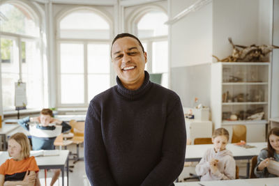 Portrait of happy male teacher standing in classroom