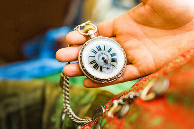 Cropped hand holding pocket watch