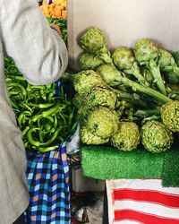 Midsection of man standing by artichokes for sale at market stall