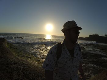 Man standing on beach against sky during sunset