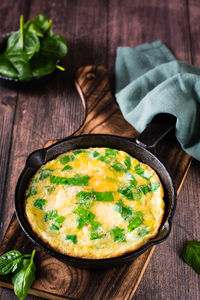 Omelet stuffed with spinach in a pan for breakfast on the table. homemade food. vertical view