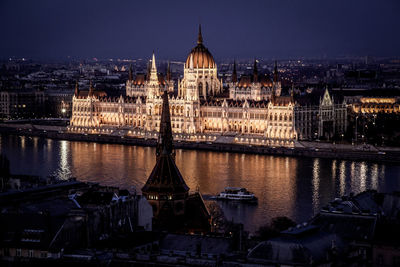 Hungarian parliament building by river in city at night