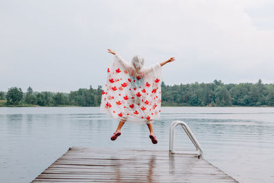 Full length of woman with umbrella on lake against sky