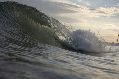 Sea waves splashing on shore against sky