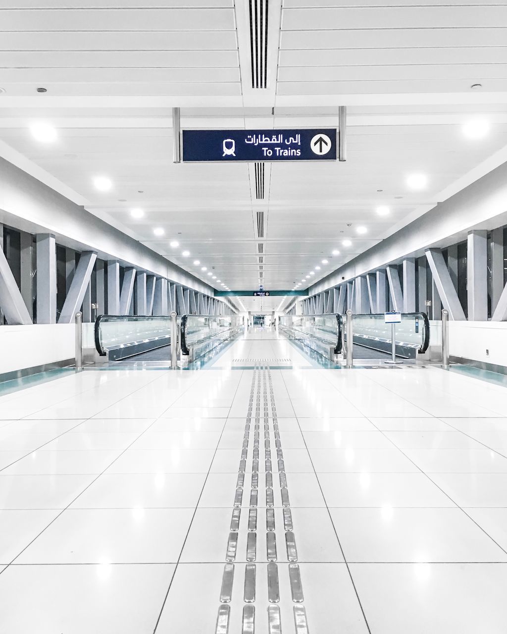 indoors, transportation, sign, architecture, illuminated, direction, communication, public transportation, text, information, built structure, subway station, no people, lighting equipment, ceiling, mode of transportation, information sign, airport, travel, arrow symbol, modern, flooring, moving walkway, tiled floor