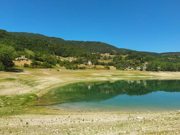 Scenic view of lake against clear blue sky