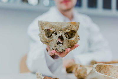 Close-up of doctor or medic hand holding human skull in white uniform