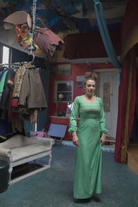 Young woan in long green dress standing in artist studio