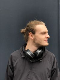 Young man looking away standing against black background