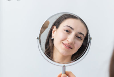 Portrait of young woman with stethoscope against white background