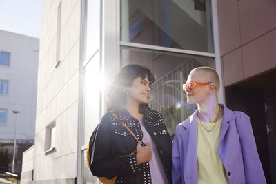 Smiling female friends or gay couple looking at each other and smiling