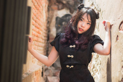 Portrait of smiling woman standing against wall