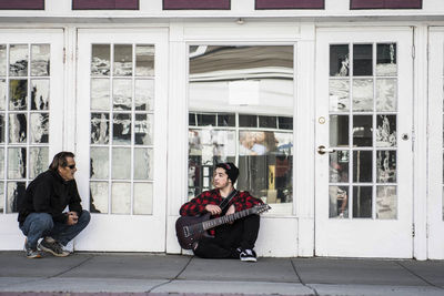 Young couple sitting on window of building