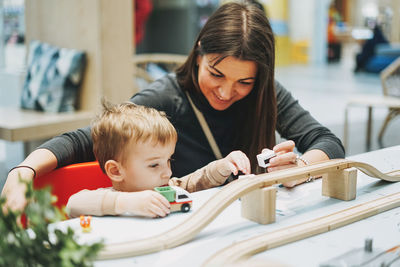 Baby boy by mother playing with toy car