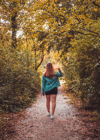 Rear view of woman walking on autumn trees