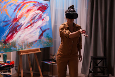 Woman holding paintbrush while wearing virtual reality headset