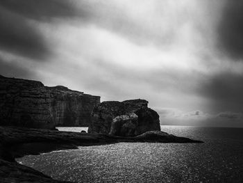 Rock formation on beach against sky