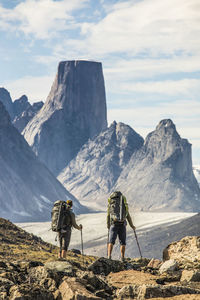 Rear view of people on rock by mountains against sky