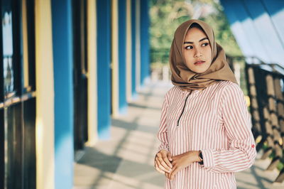 Woman wearing hijab while standing on corridor