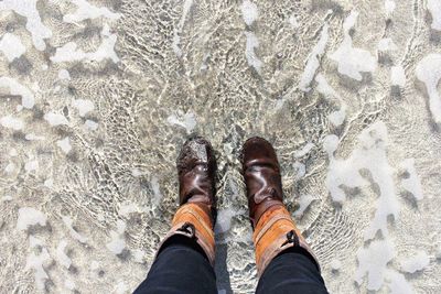 Low section of man standing on sand